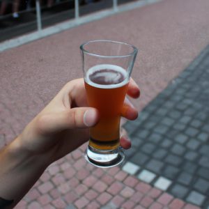 Person holding beer glass, tasting